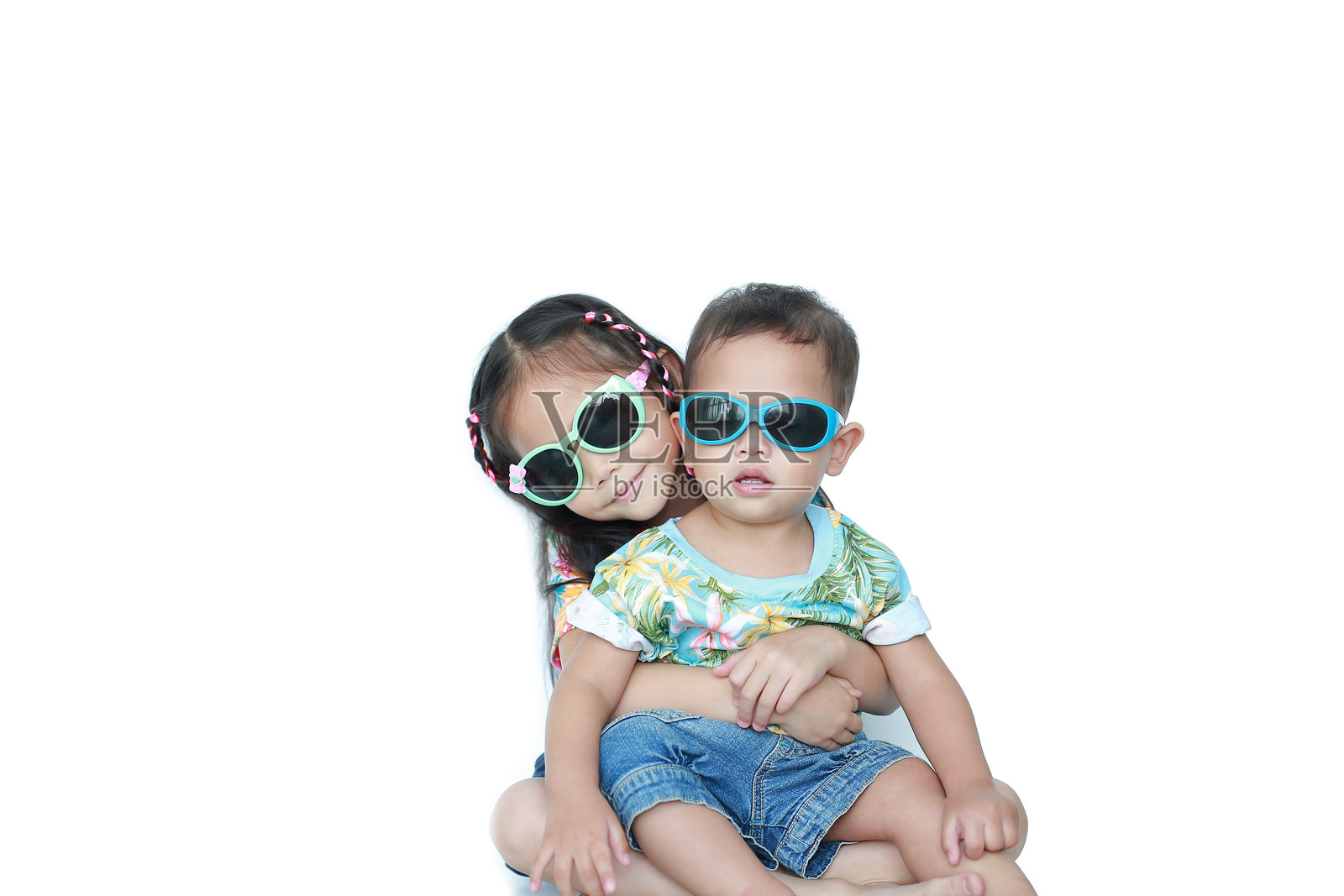 肖像小亚洲妹妹拥抱弟弟穿着花夏装和太阳镜孤立在白色背景。夏季和时尚的概念。照片摄影图片