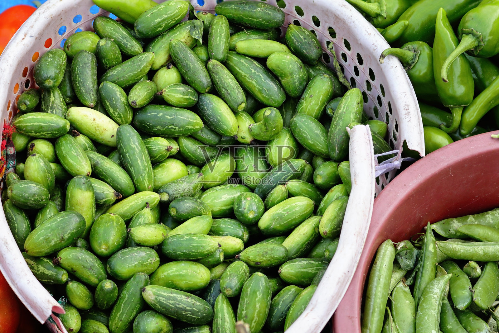 新鲜的绿藤瓜或苦瓜散落在一个地方，市场上出售的苦瓜堆，印度藤瓜的堆叠，常见的三角瓜，小黄瓜，爬藤瓜。照片摄影图片