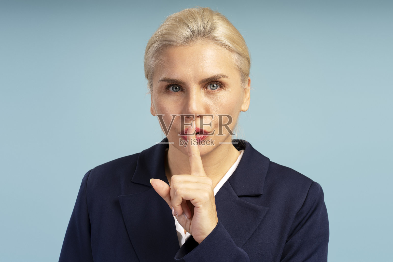 商务女性在蓝色背景上做出安静手势照片摄影图片