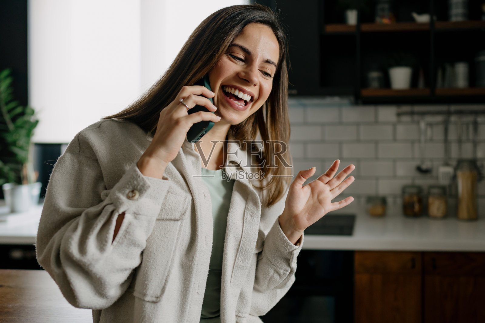 年轻女性在厨房里打电话时笑着照片摄影图片