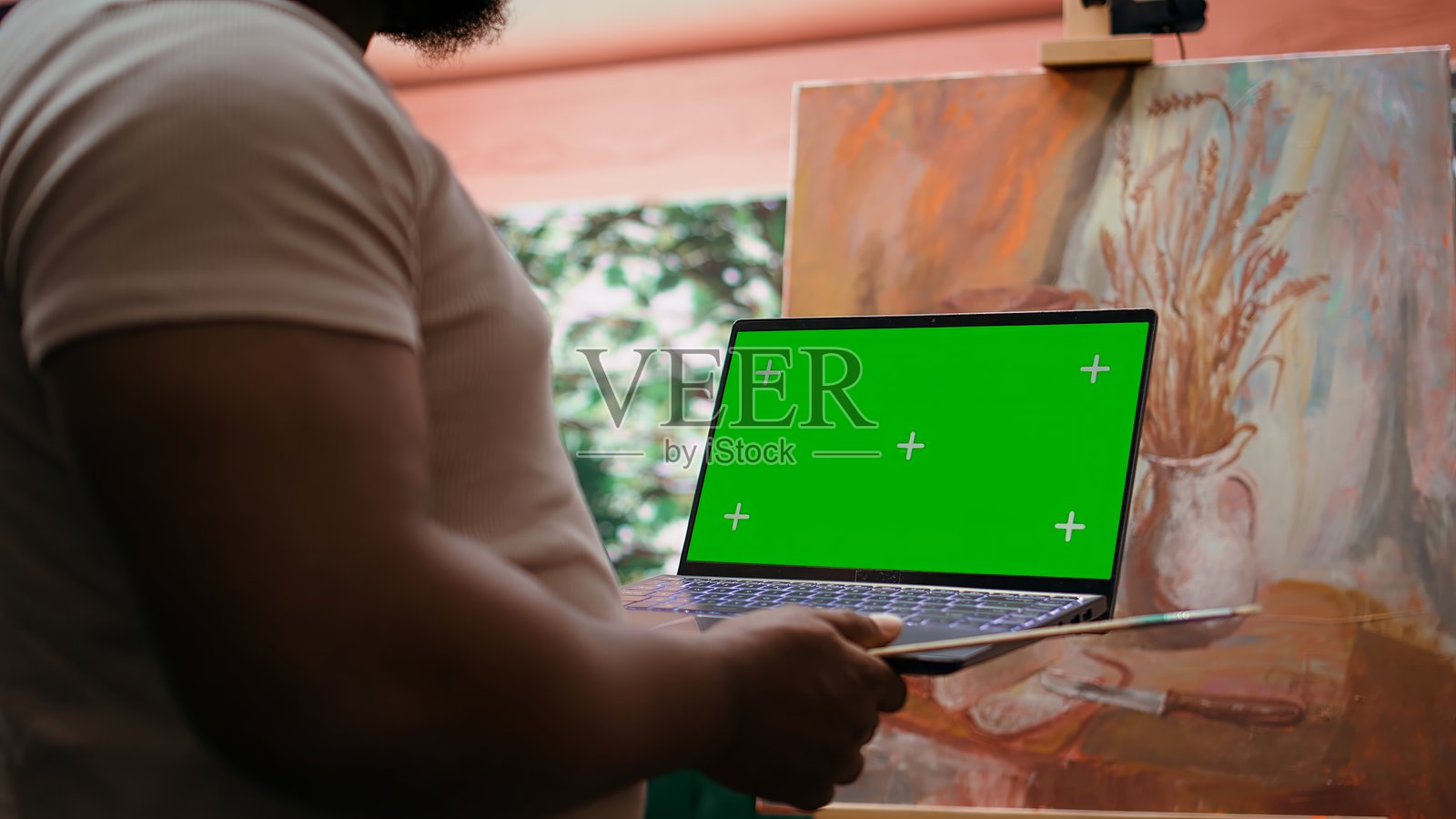 非裔美国艺术家在艺术工作室中手持带有绿幕的设备进行展示照片摄影图片