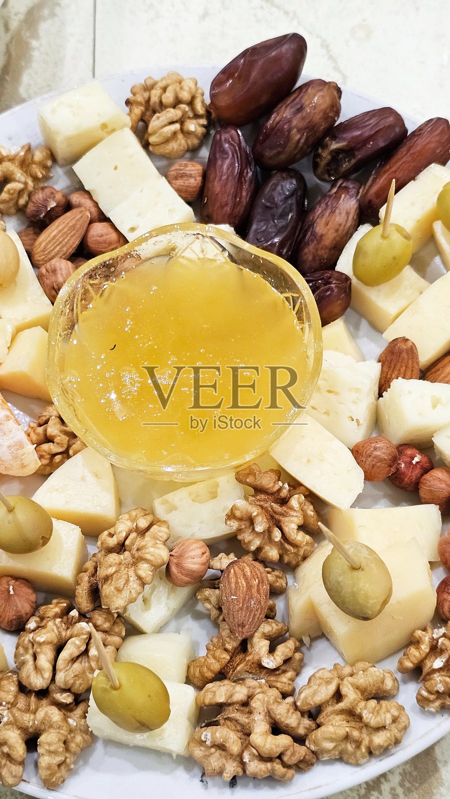 白盘上的奶酪拼盘与蜂蜜照片摄影图片