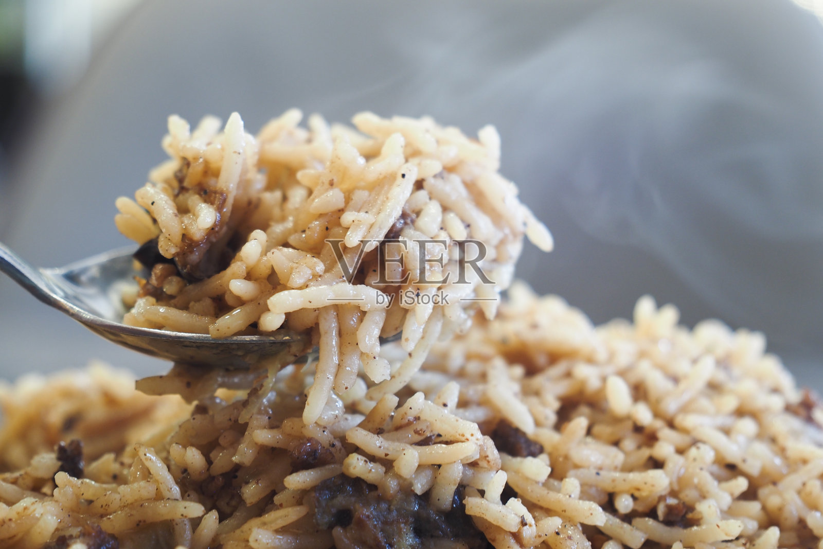 一盘美味蒸汽腾腾的松软米饭优雅地 resting 在勺子上，随时准备上桌。照片摄影图片