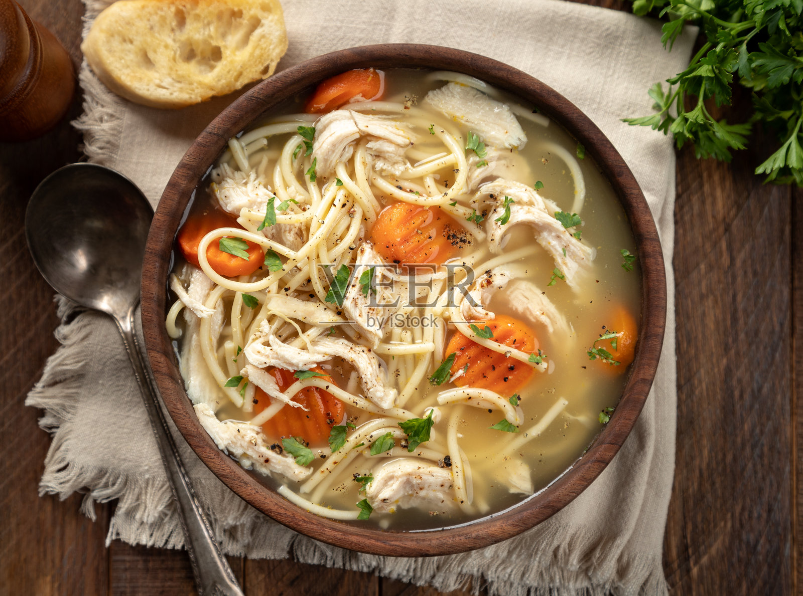一碗鸡肉面条汤，上面放着胡萝卜，放在餐巾上照片摄影图片