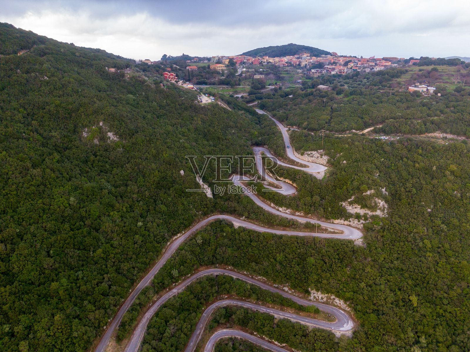 蜿蜒的山路俯瞰图，四周被郁郁葱葱的森林环绕照片摄影图片