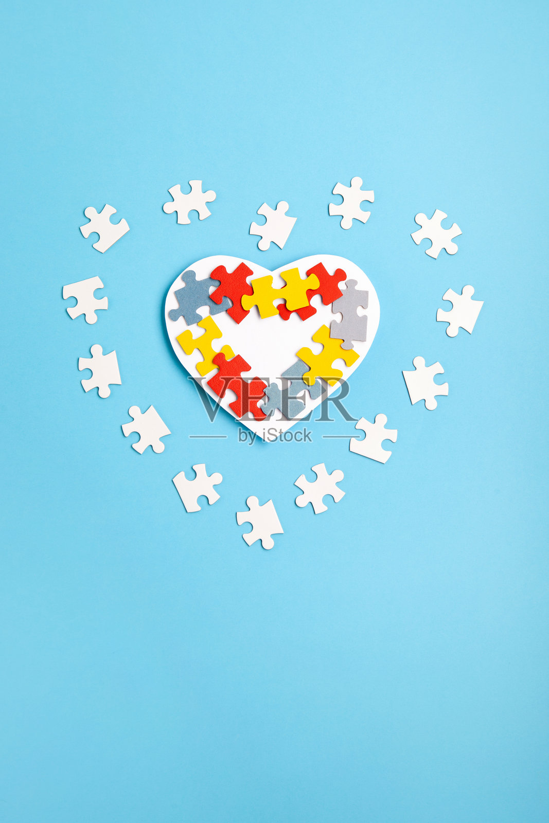 自闭症意识日，世界自闭症日，4月2日。蓝色背景上的白色心形和五彩拼图。照片摄影图片