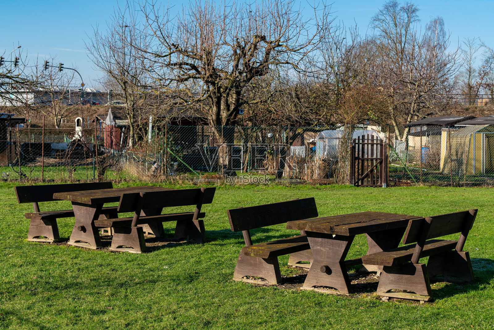 阳光明媚的公园里，周围环绕着树木和花园的野餐桌照片摄影图片