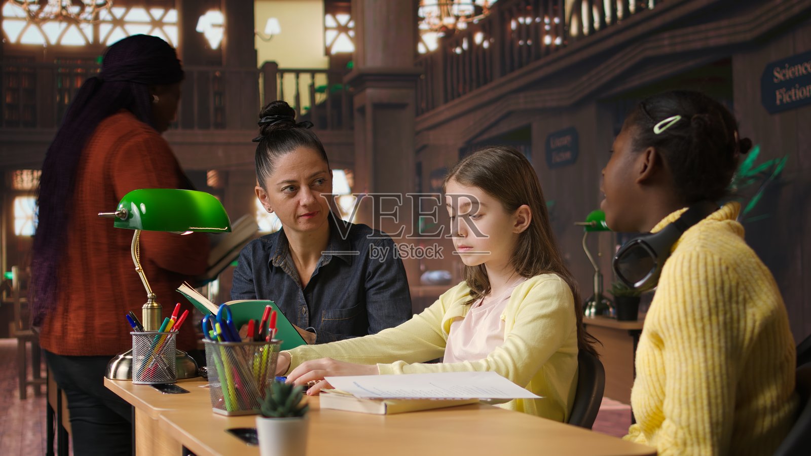 女导师在学校图书馆指导女学生照片摄影图片