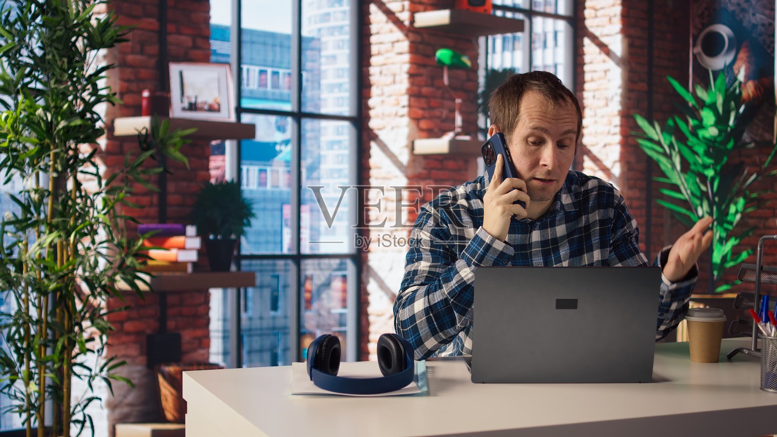 在家办公室的经理坐在桌子前，使用笔记本电脑拨打员工电话。照片摄影图片