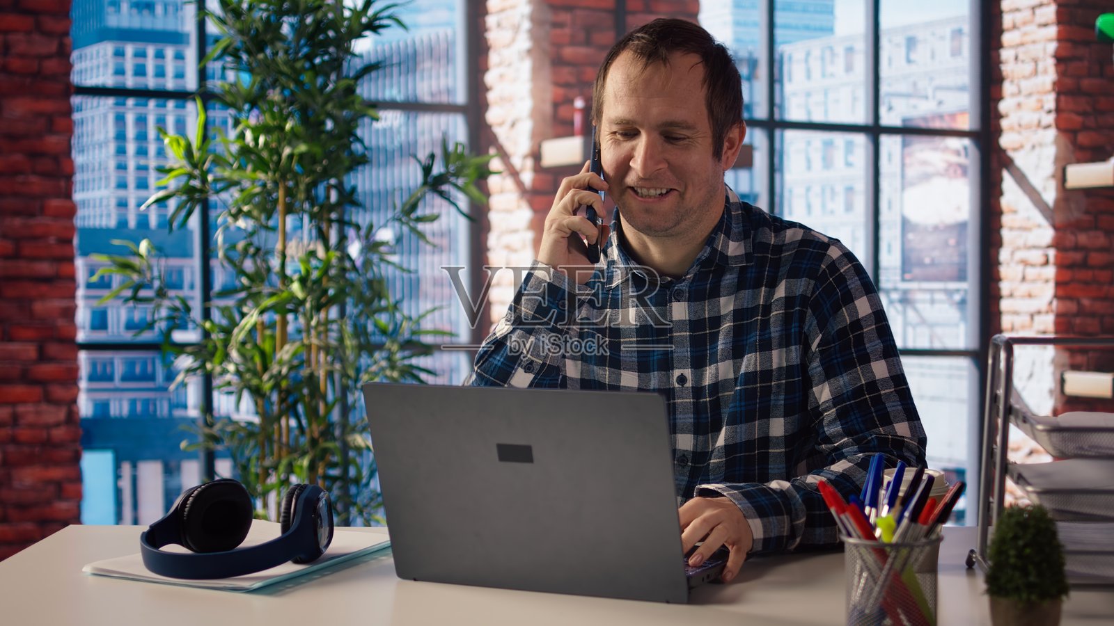 在家办公室工作的自由职业者坐在桌子前，接听电话。照片摄影图片