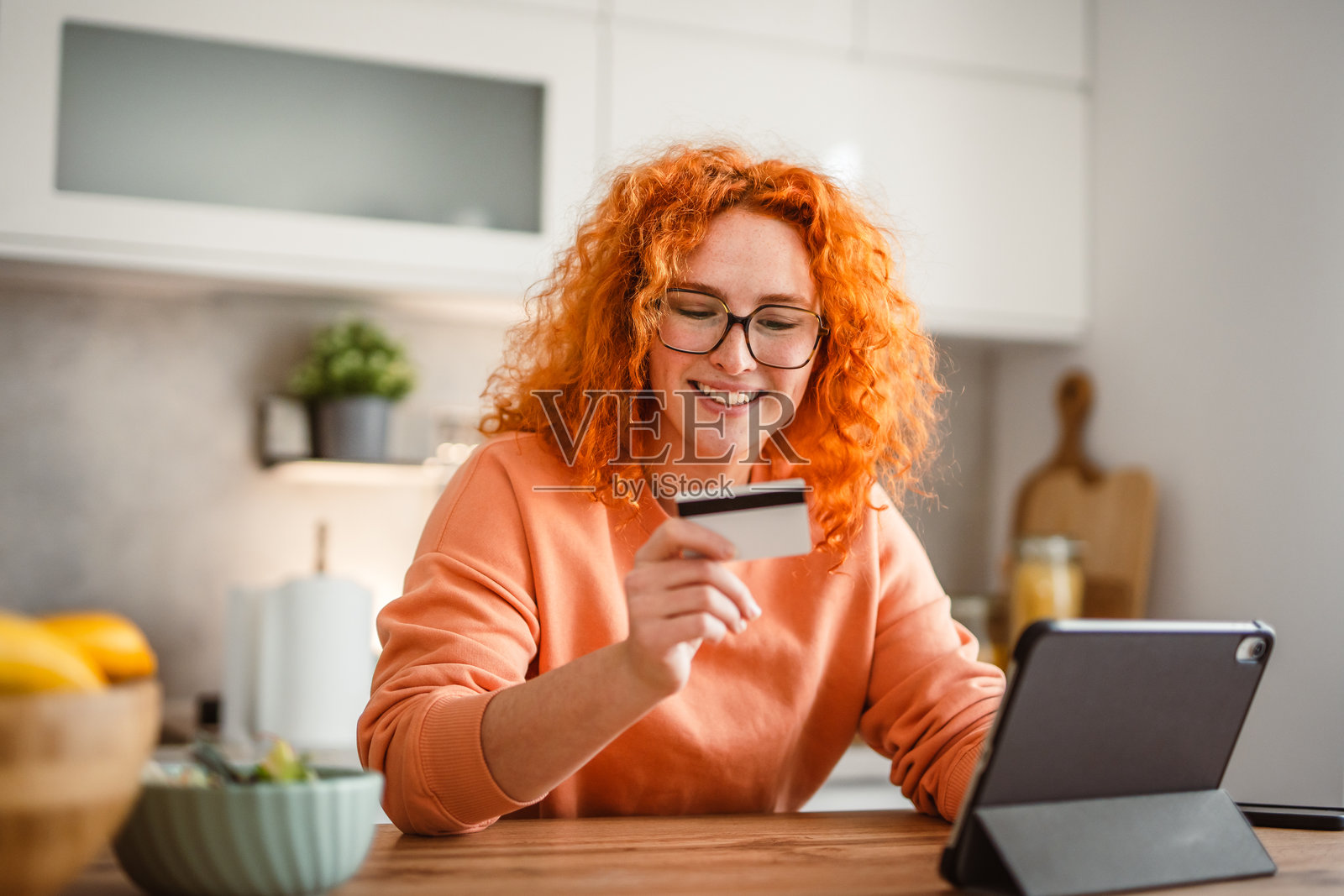 女人吃沙拉，使用平板电脑和信用卡付款。照片摄影图片