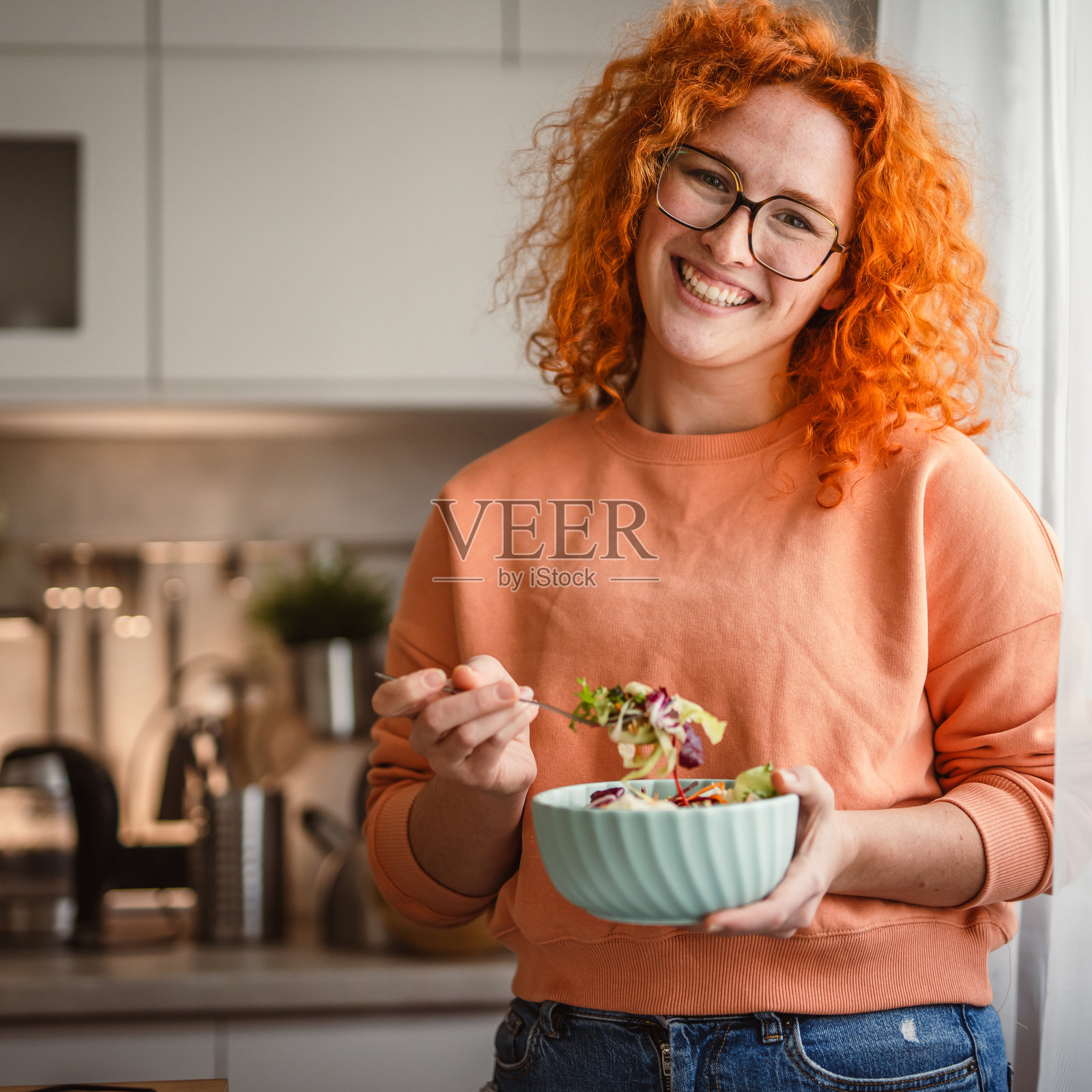 早晨在厨房里，漂亮健康的女人吃沙拉的肖像照片摄影图片