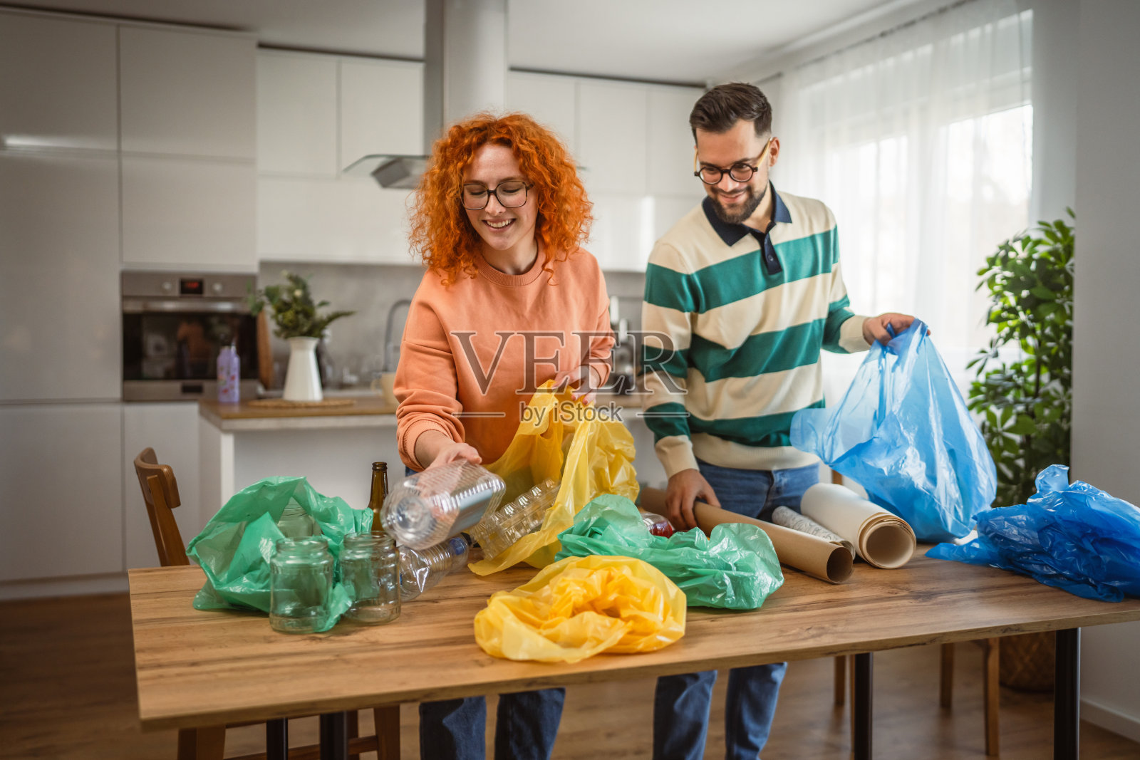 男女在家中进行回收，分类废弃的塑料、纸张和玻璃。照片摄影图片