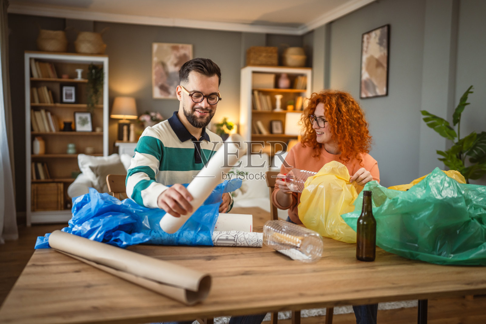 男女在家中进行回收，分类废弃的塑料、纸张和玻璃。照片摄影图片