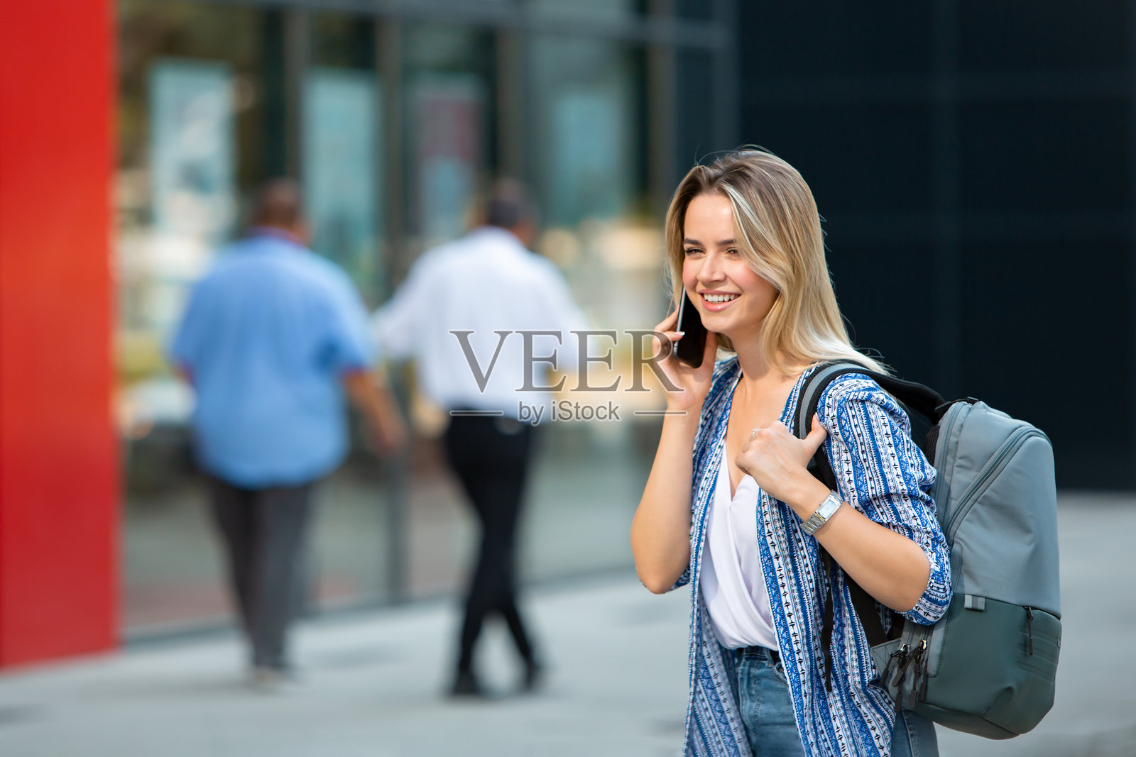 年轻金发女性在现代办公楼外打电话照片摄影图片