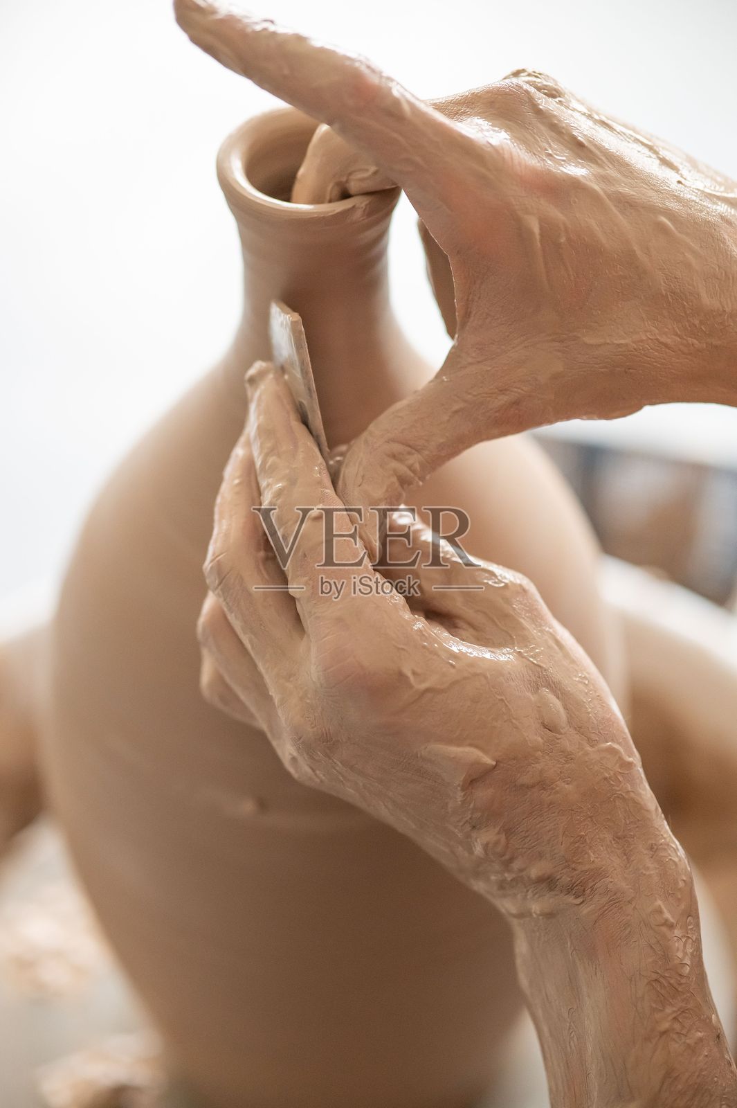 一位陶艺师在陶轮上使用工具。特写镜头展示一位男性的手。竖版照片。照片摄影图片