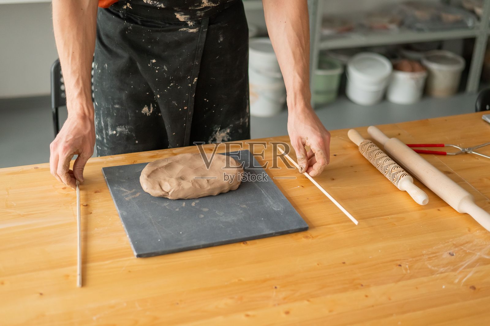 陶艺师的手在近距离滚动粘土。照片摄影图片