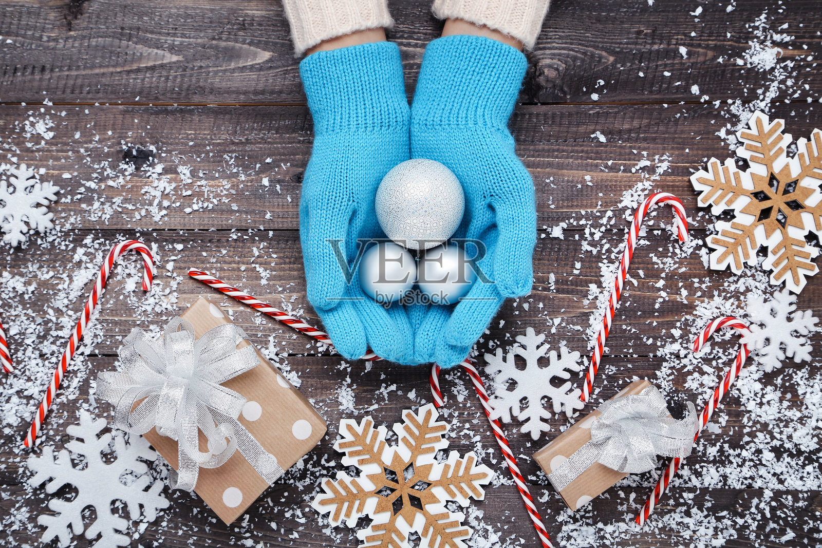 戴着针织手套的手与圣诞装饰品和礼品盒放在木桌上照片摄影图片