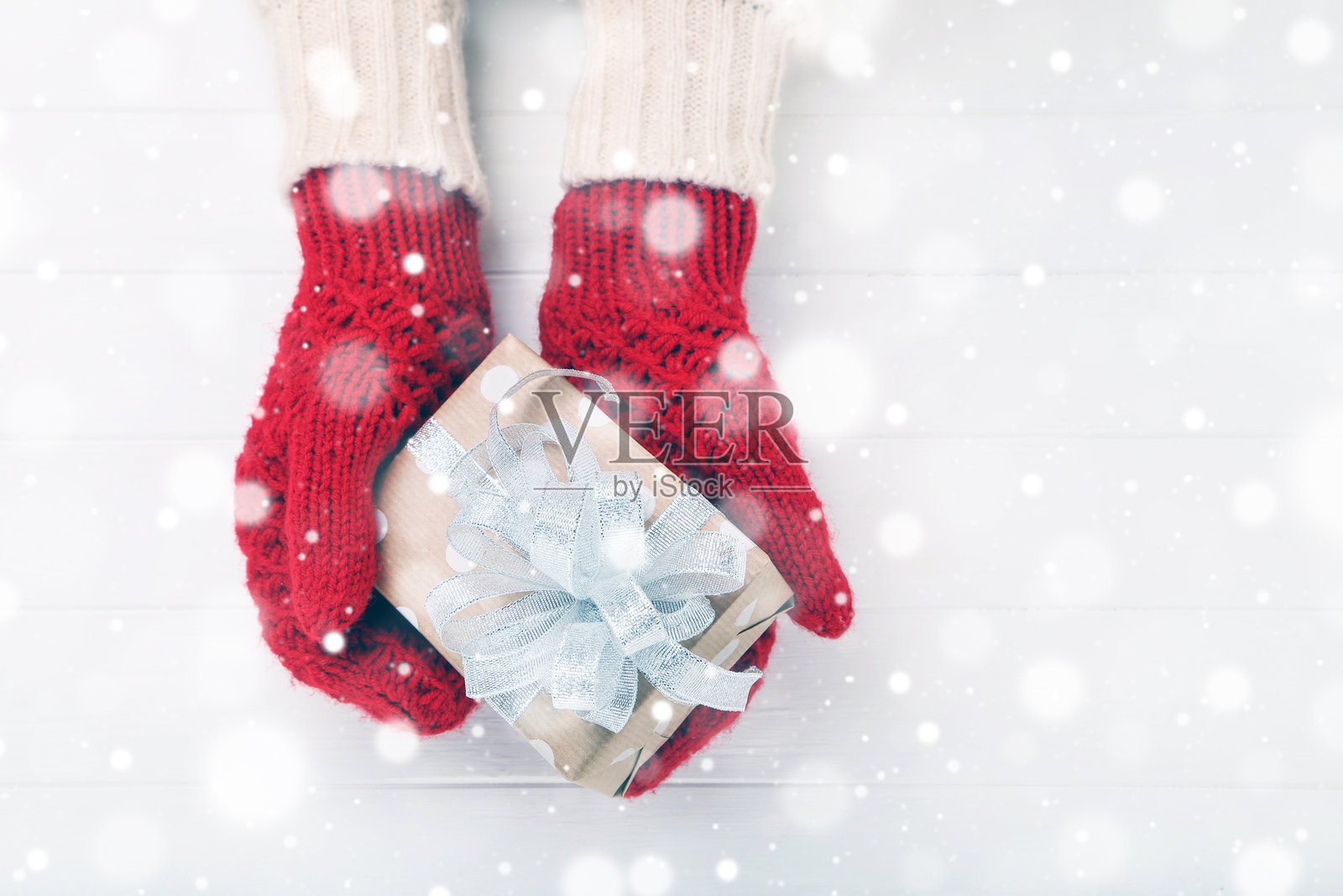 戴着针织手套的手放在白色木桌上的礼物盒旁照片摄影图片