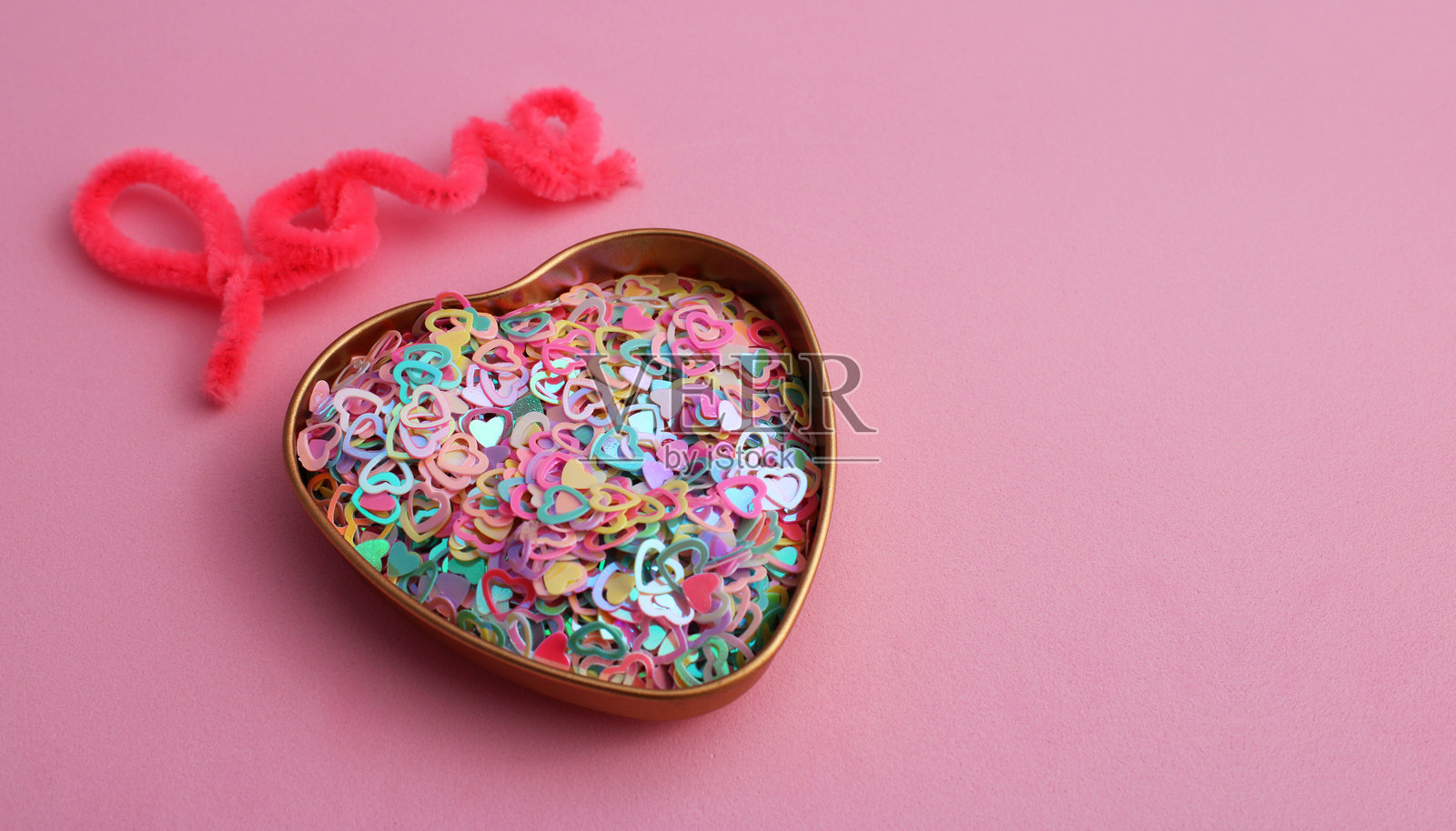 “爱”字旁边有一个装满五彩缤纷心形的容器照片摄影图片