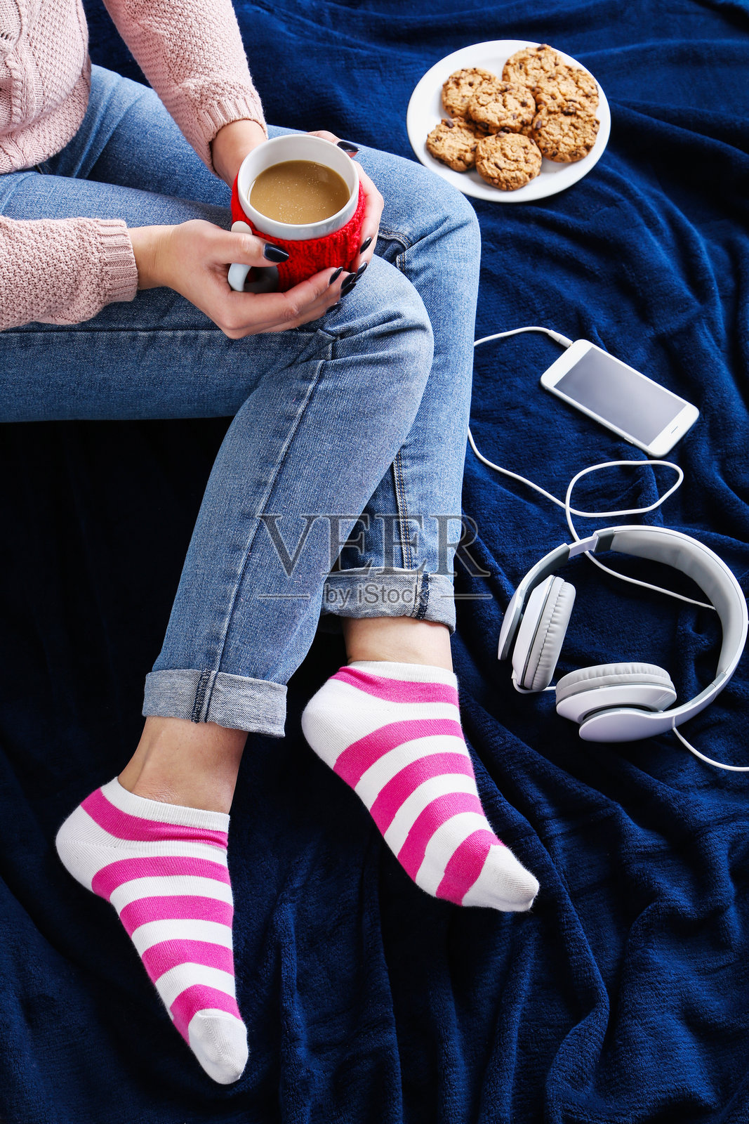 坐在蓝色格子布上的女人手里拿着一杯咖啡照片摄影图片