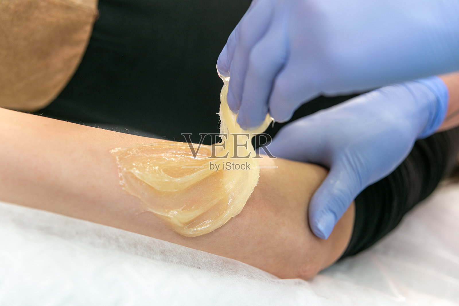 使用糖膏或蜜蜡进行手臂脱毛的美丽女性过程照片摄影图片