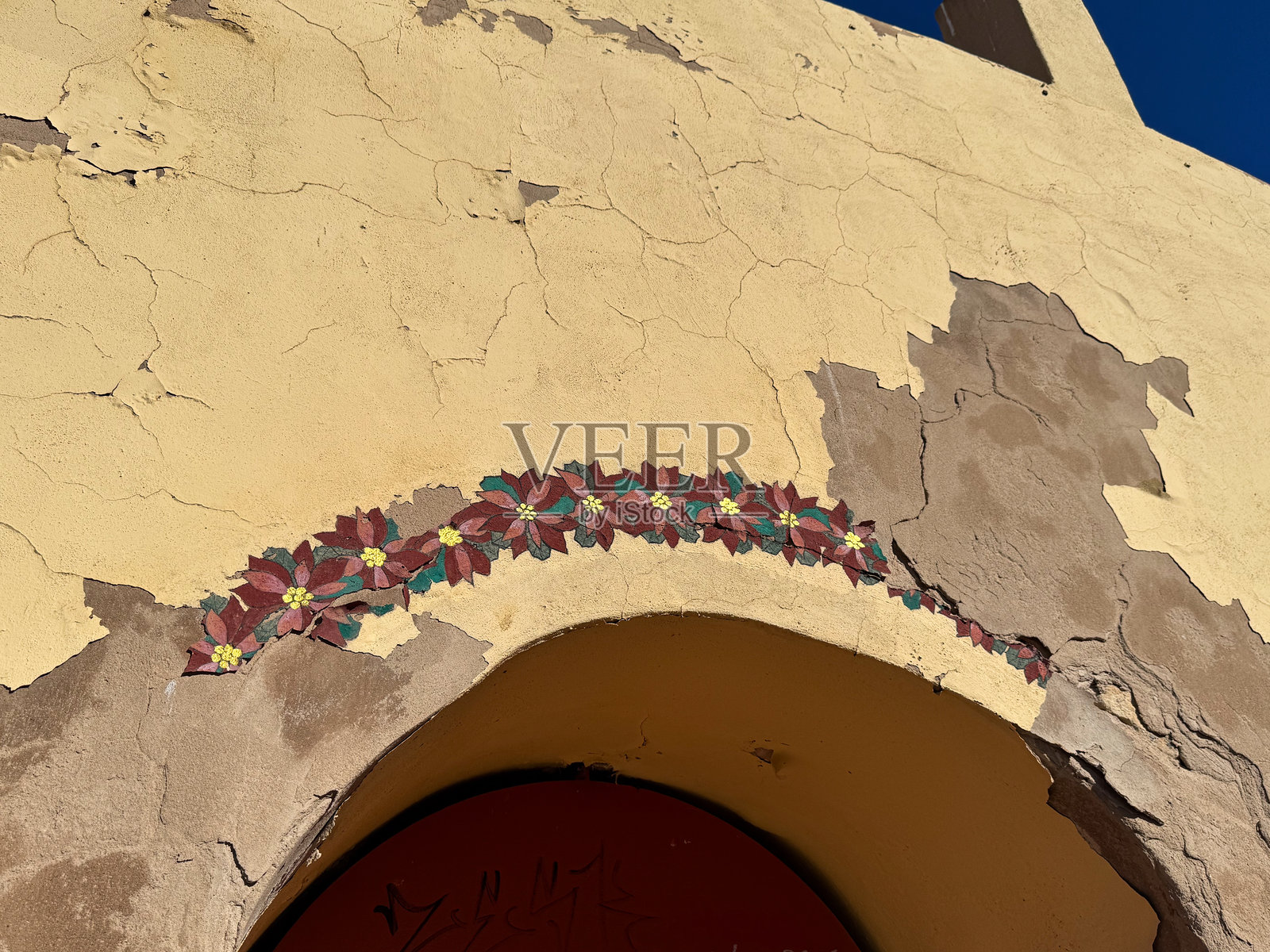 风化的建筑外立面，拱形入口上装饰着花卉图案照片摄影图片