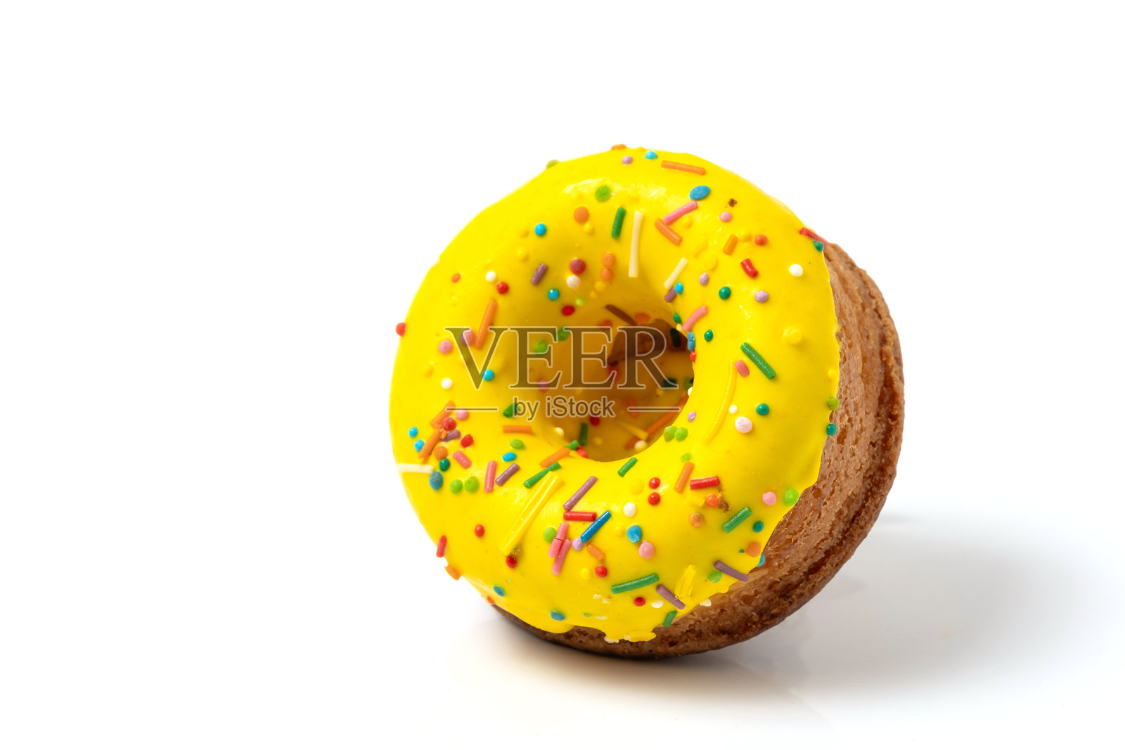带有黄色糖霜和五彩撒糖的甜甜圈，突出显示在白色背景上。照片摄影图片