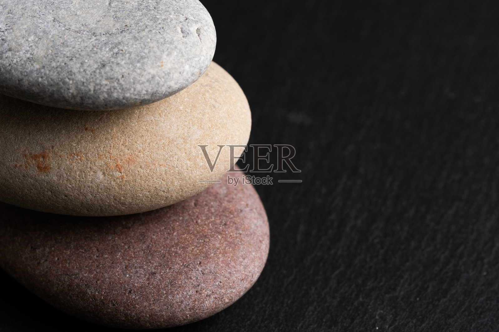 黑色石头背景上的卵石堆。禅意概念。照片摄影图片