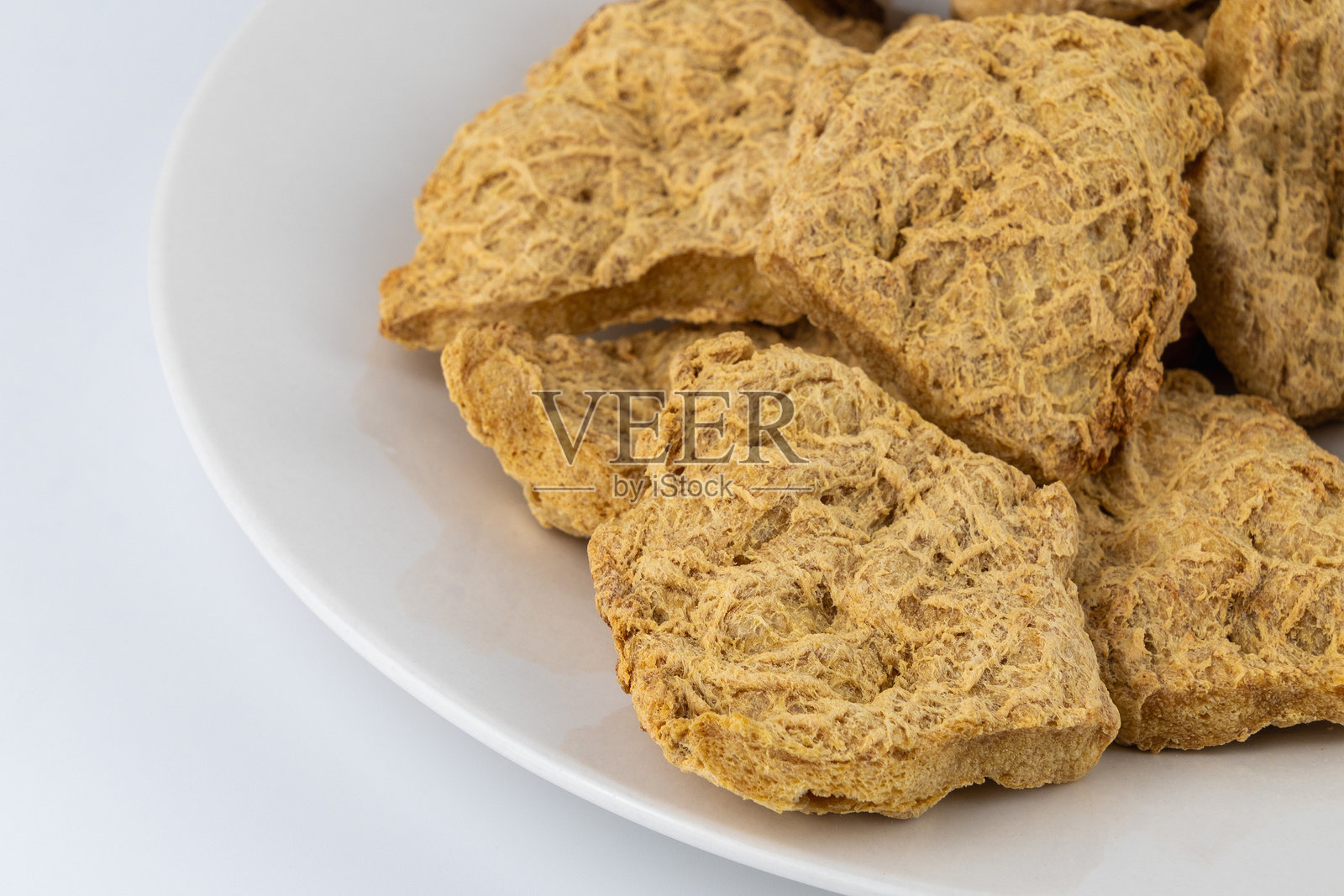 白盘上的干豆肉块。纹理植物蛋白。照片摄影图片