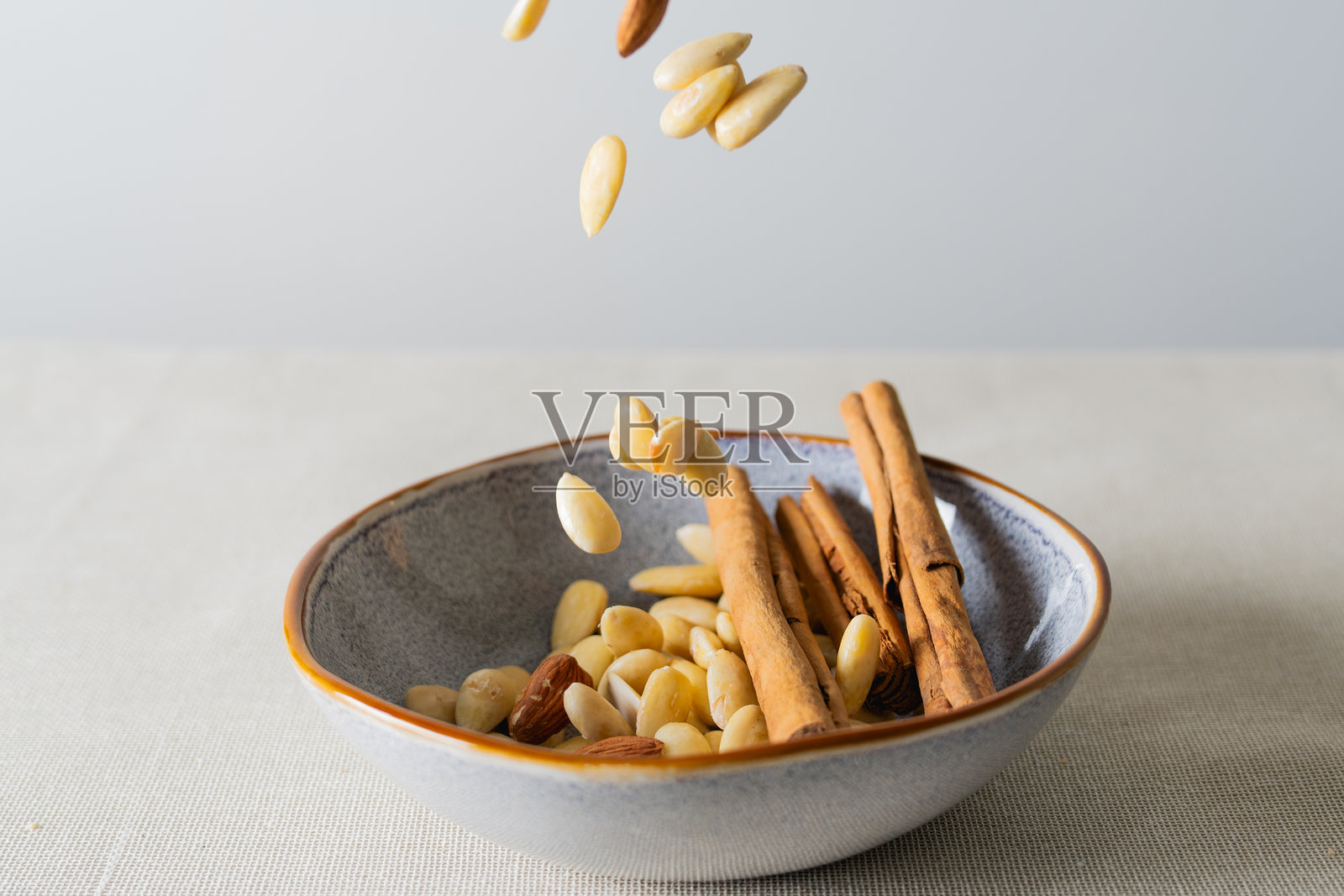 杏仁掉入装有肉桂棒的碗中照片摄影图片