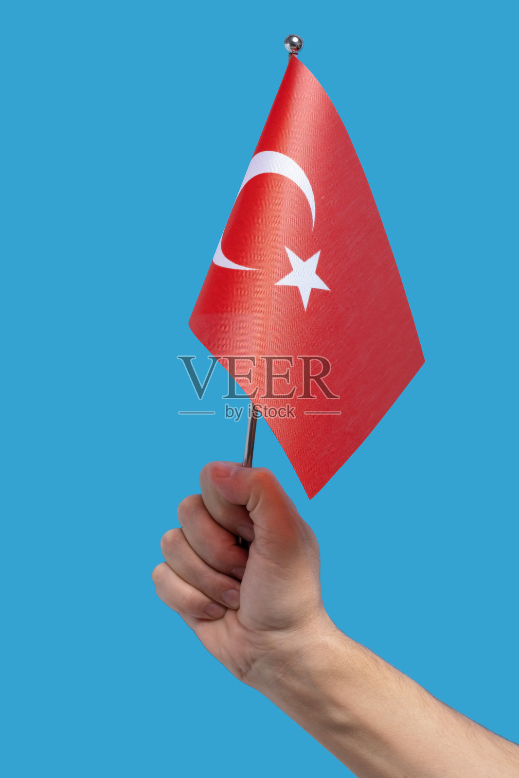 手握土耳其国旗，背景为蓝色。照片摄影图片