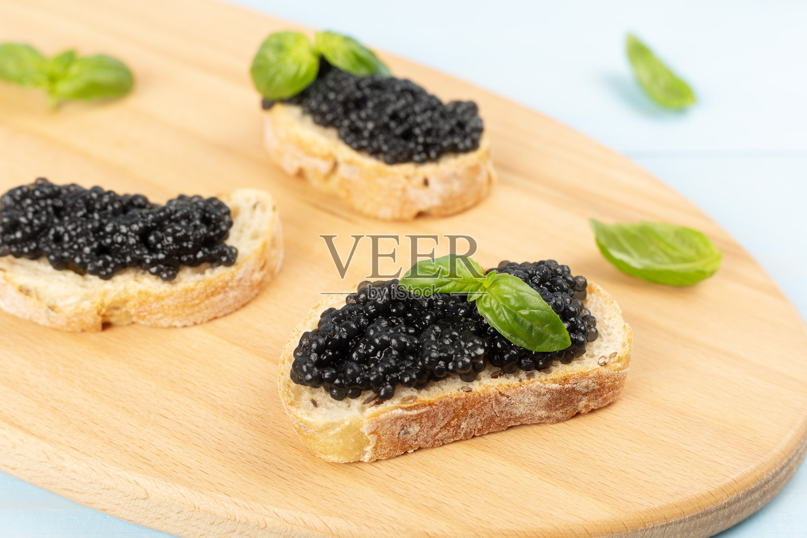 木桌上摆放着涂有黑鱼子酱的面包片照片摄影图片