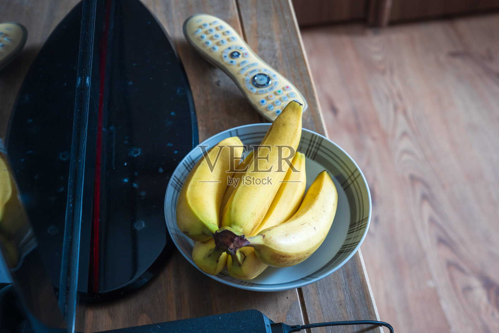 新鲜成熟的香蕉放在电视旁的桌子上照片摄影图片