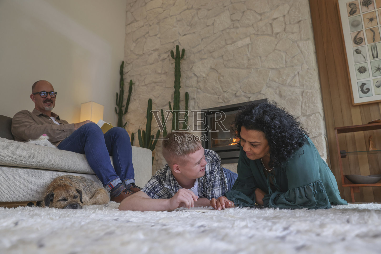 母亲和成年儿子在客厅阅读，父亲坐在沙发上照片摄影图片