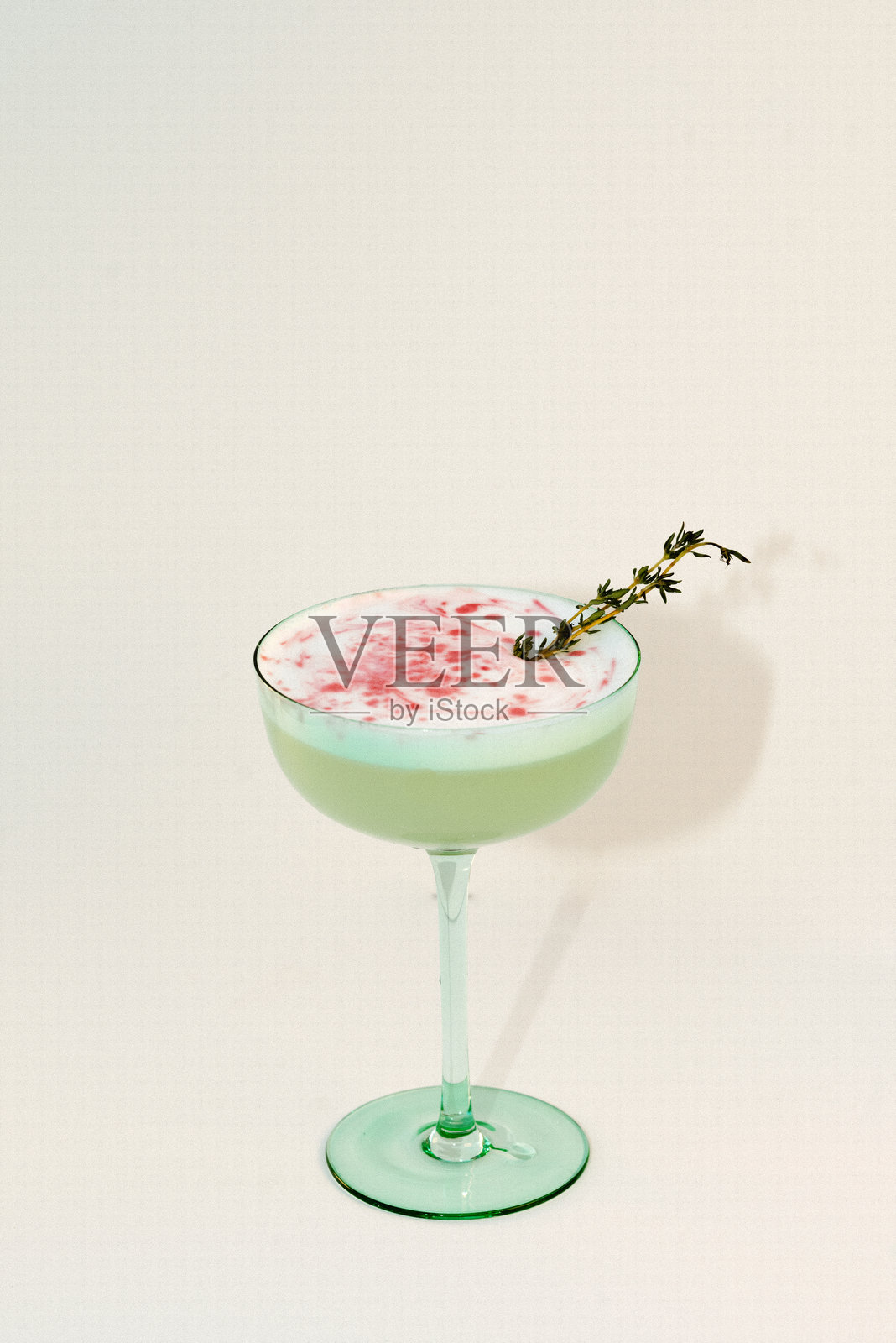 优雅的鸡尾酒在香槟杯中，顶部有泡沫、装饰和红色淋酱。照片摄影图片