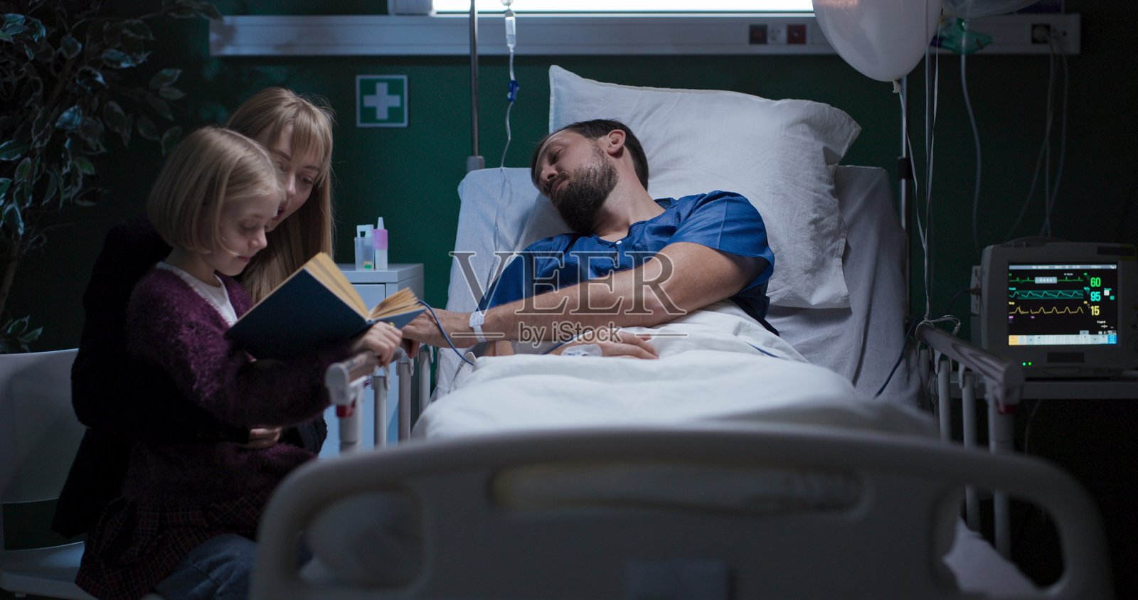 男人在睡觉，孩子在读书，母亲静静地坐在旁边。照片摄影图片