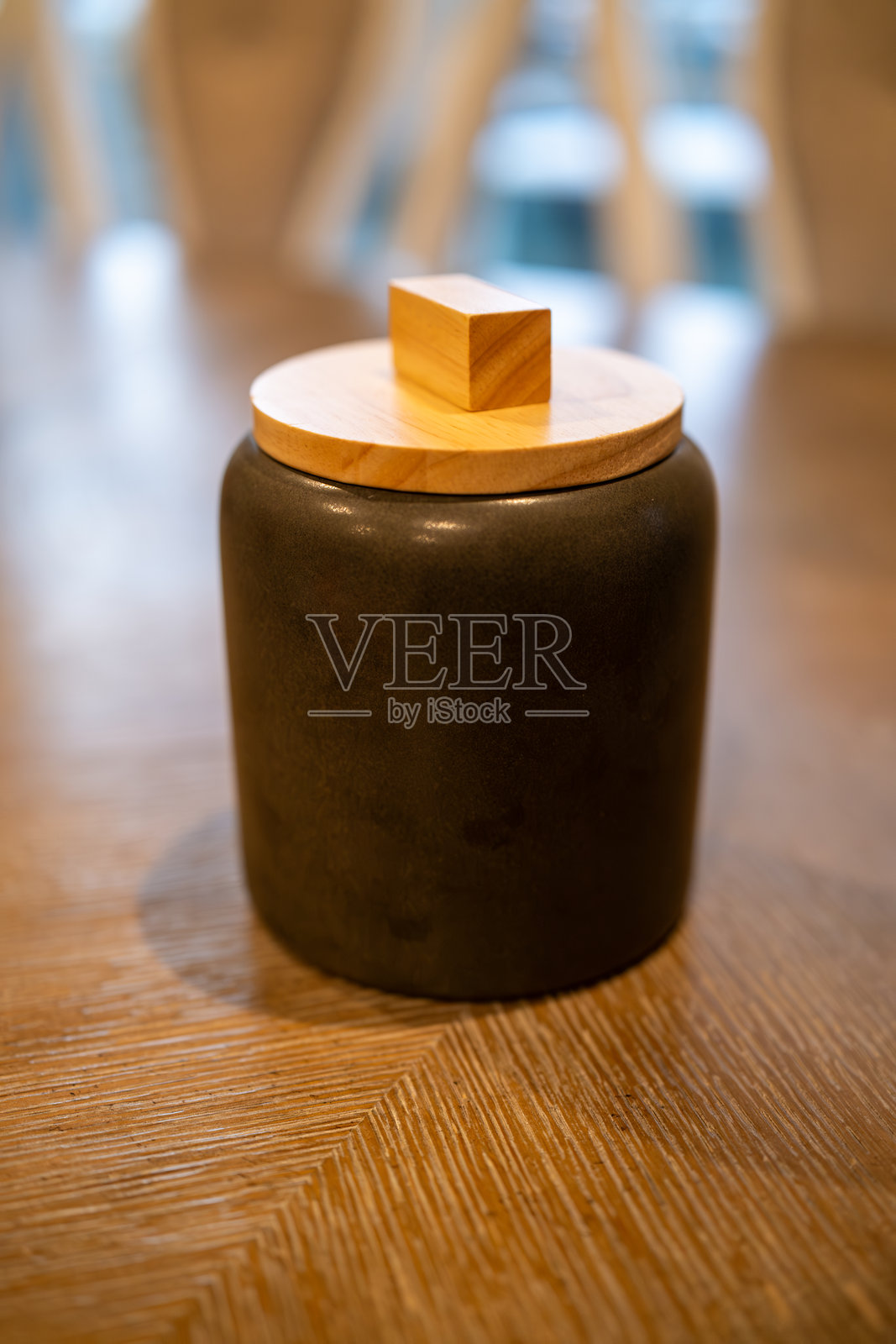 独特的黑色罐子配木盖，放在现代室内环境中有纹理的木桌上照片摄影图片