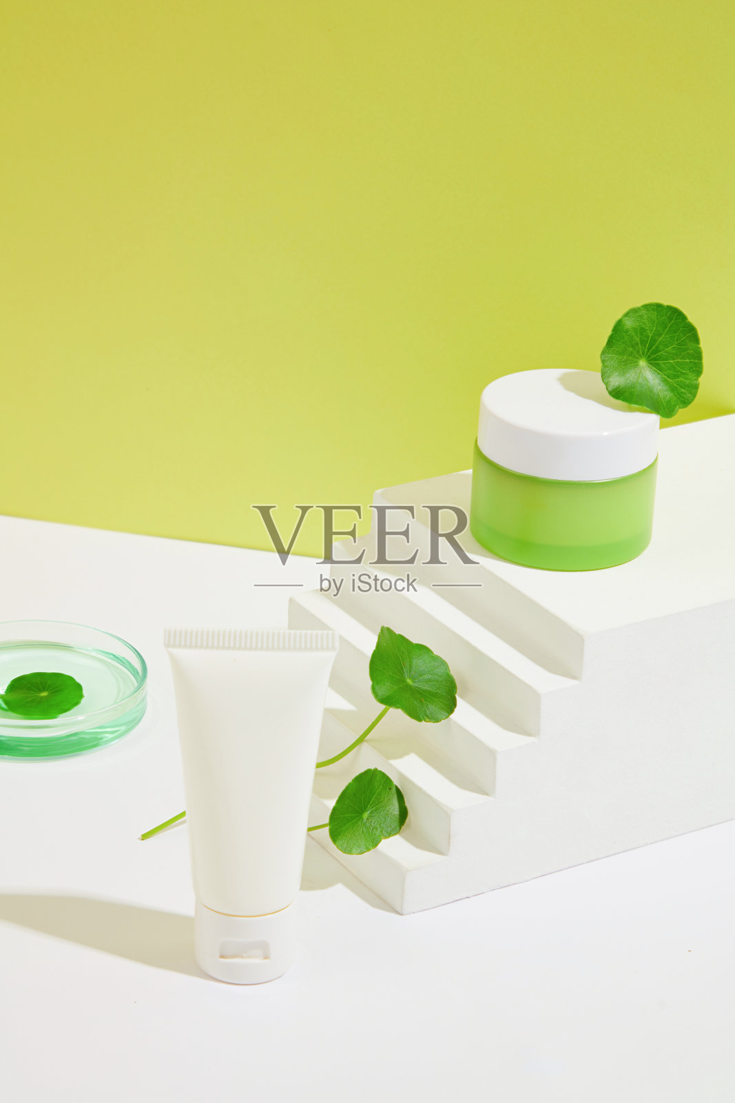 一罐绿色洗液和一管洗面奶放在一个白色的平台上，上面放着草。护肤用天然美容产品。关闭了。照片摄影图片