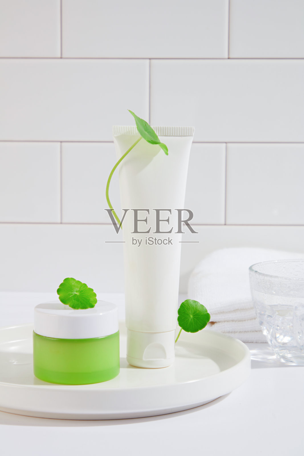 化妆品套装的特写镜头，其中包含草提取物，放置在一个空白标签的白色陶瓷板上。Gotu kola具有再生细胞、消毒和愈合受损皮肤的作用。照片摄影图片