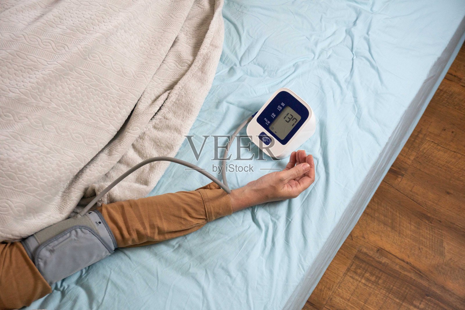 年轻女子在家床上测量他的血压。自我血压和心率照片摄影图片