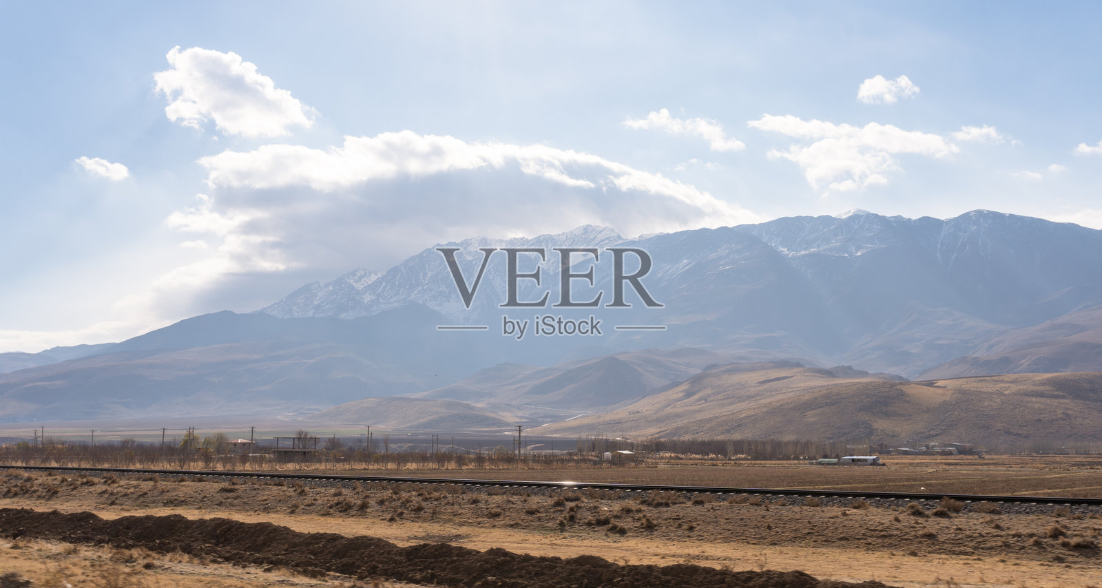 群山环绕的丘陵山谷，远处可见雪山照片摄影图片