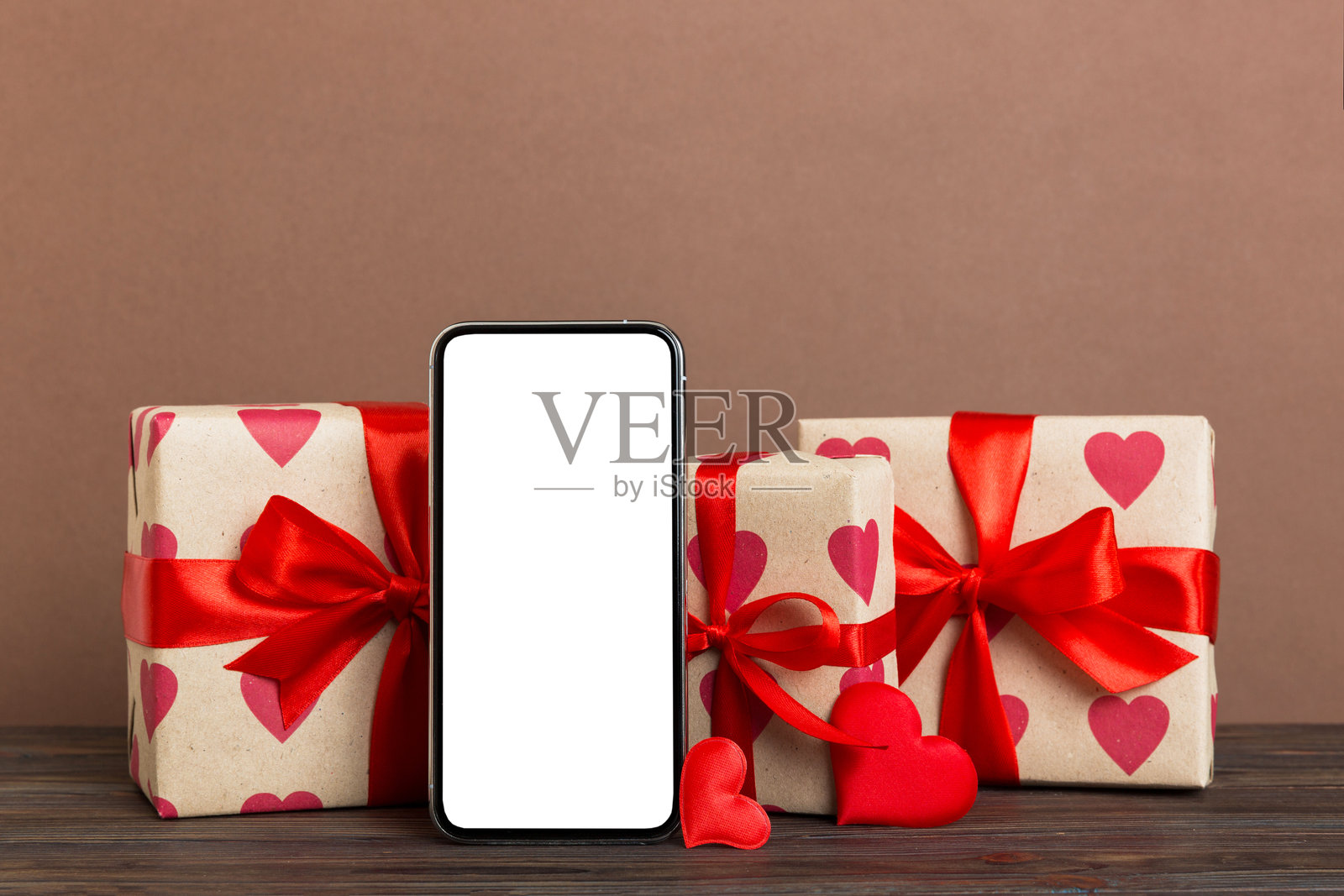 手机用空白屏幕在彩色背景上加上心形图案，日历和礼盒，情人节概念透视平铺照片摄影图片