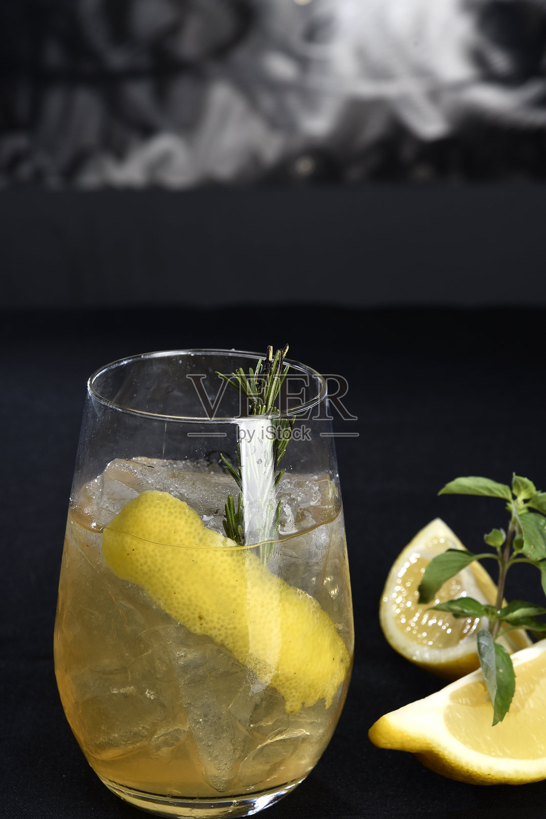 清爽的酒精饮料，有浆果、冰伏特加和杜松子酒，柠檬皮装在玻璃杯里，放在柜台上，背景模糊照片摄影图片