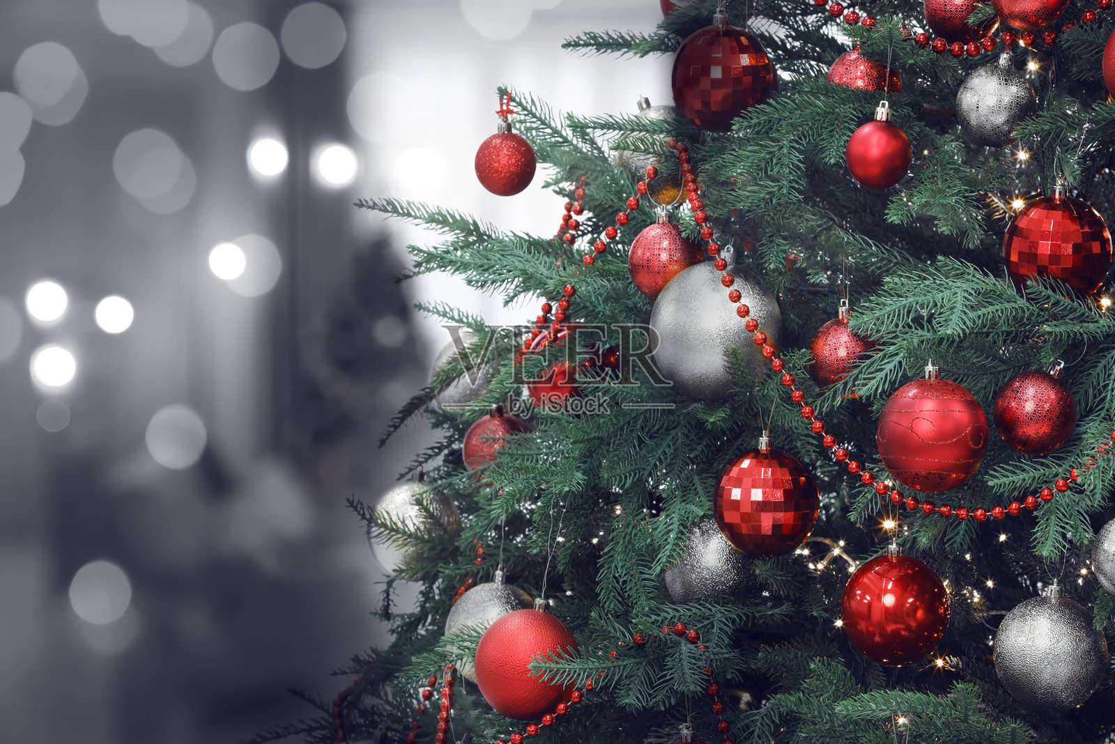 圣诞树上装饰着红色和银色的节日球，背景模糊，散景效果。文本空间照片摄影图片