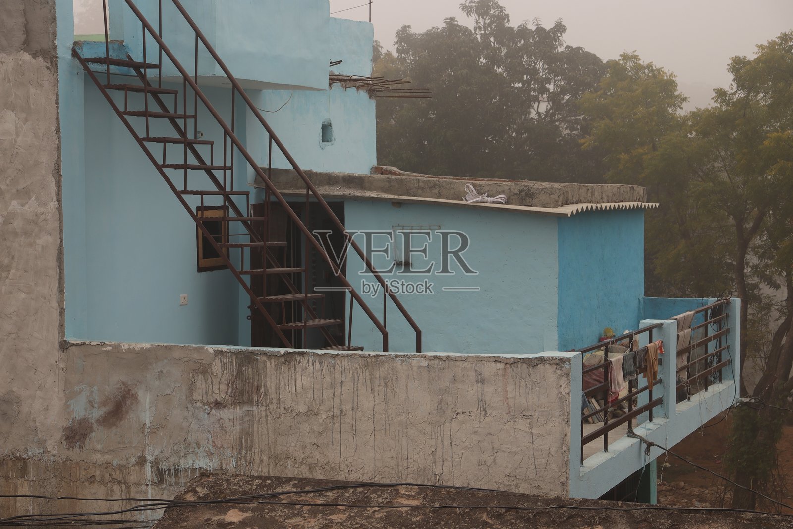 一座蓝色的印度房子，用水泥和砖墙建造，阳台上有铁黑色的楼梯照片摄影图片