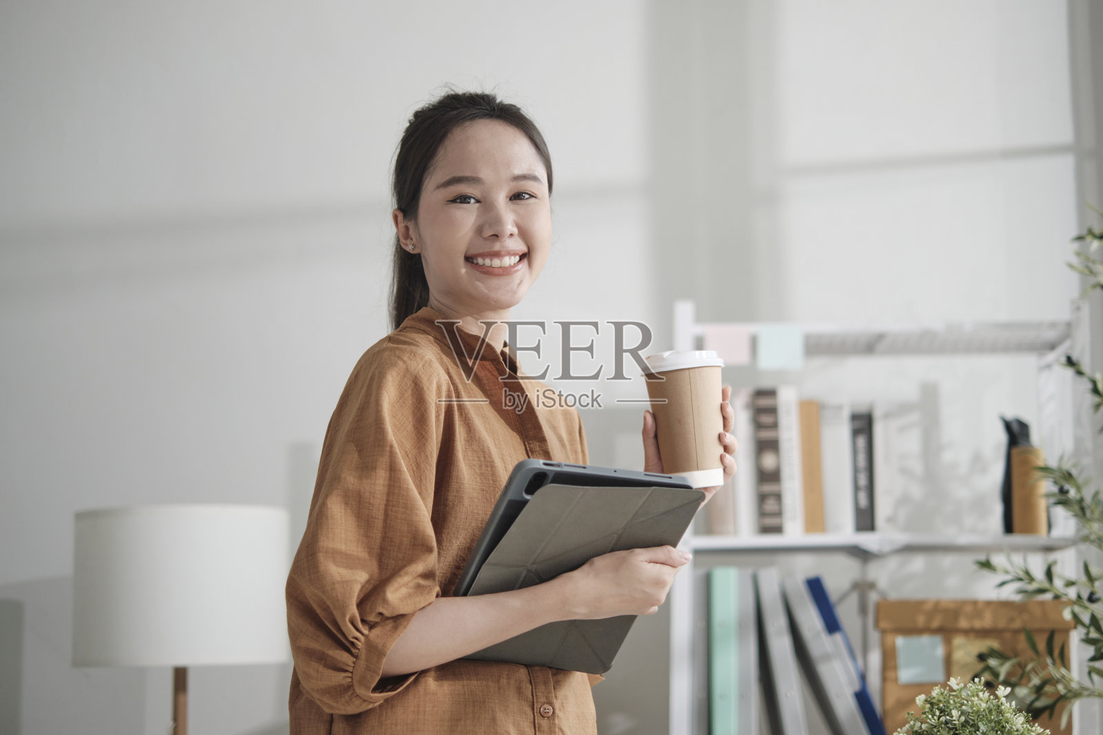 美丽的亚洲女商人在休闲的小型办公室里使用平板电脑。照片摄影图片