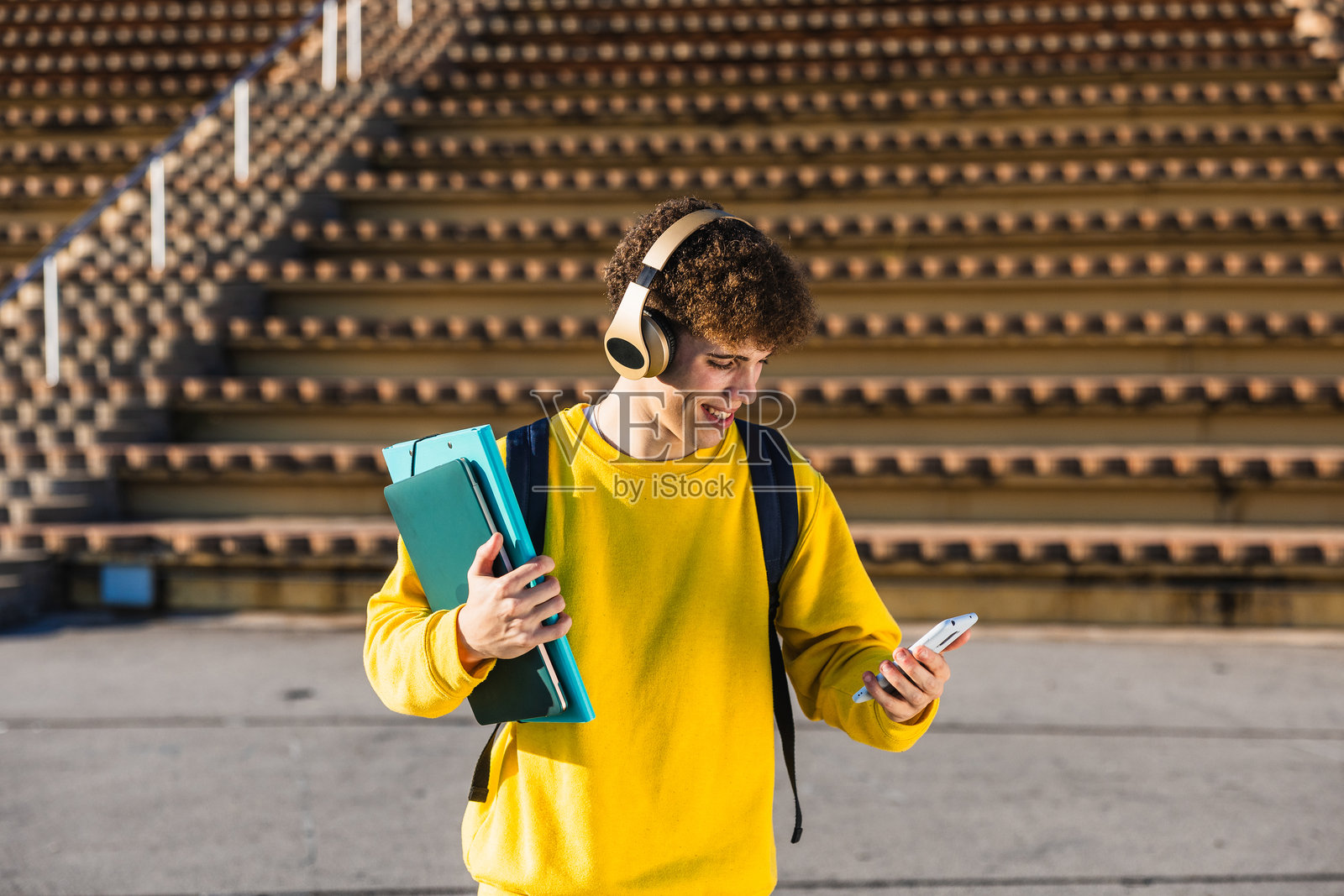 微笑的学生在户外听音乐并使用智能手机照片摄影图片