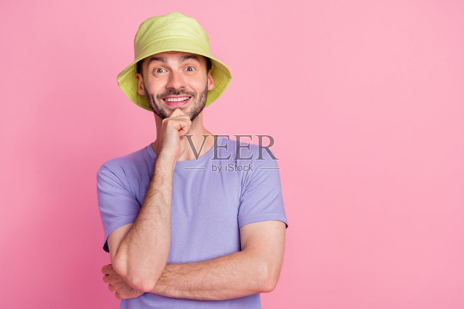 一位英俊成功的男孩用手触摸脸庞，站在粉色背景的空旷空间中，展现出做出良好决策的自信。照片摄影图片