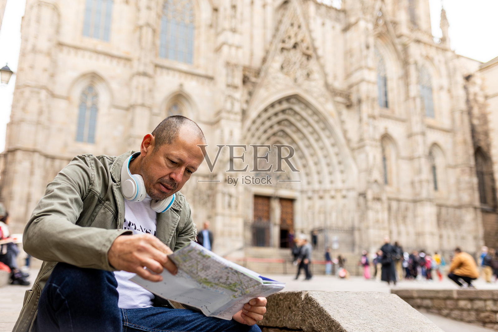 拉丁裔游客在巴塞罗那度假时咨询街道地图并佩戴耳机照片摄影图片